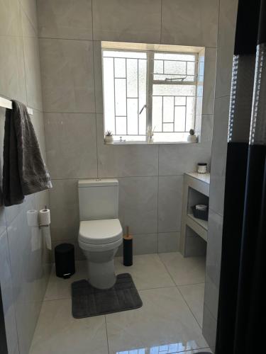 a white bathroom with a toilet and a window at Mario & Luiza's Place - Cozy Stay with Pool & Braai in Worcester