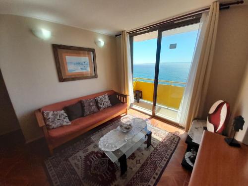 a living room with a couch and a table and a large window at Departamentos Playa Bellavista 2025 in Tomé