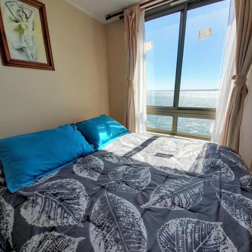 a bedroom with a bed with a large window at Departamentos Playa Bellavista 2025 in Tomé