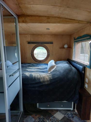 un lit dans une petite pièce avec une fenêtre dans l'établissement La 24h Roulotte, à Parigné-lʼÉvêque