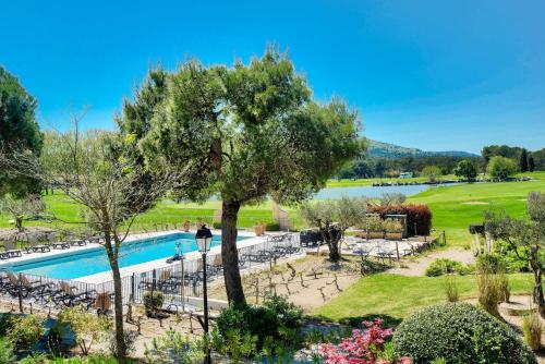 un complexe avec une piscine et un arbre dans l'établissement Résidence Hôtel du Golf de Pont Royal - maeva Home - Appartement climatisé 2 pièces 4 personnes - Prestige - super Home MAE-8801, à Mallemort