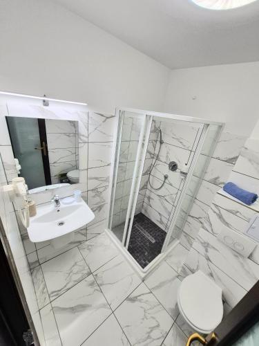 a white bathroom with a shower and a sink at Vila Kos in Mamaia Nord