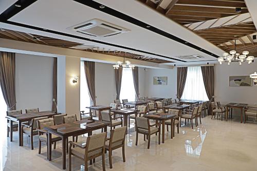 a dining room with tables and chairs and windows at Emily Grand Palace in Samarkand