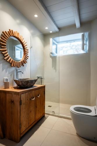 a bathroom with a sink and a toilet and a mirror at Nerea Sunset View Apartment in Agia Irini Paros