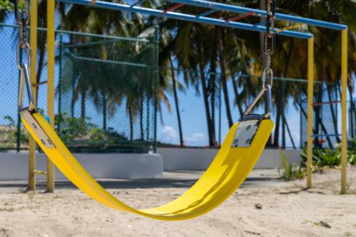 a yellow swing at a playground with palm trees at Mi estadía in San Juan