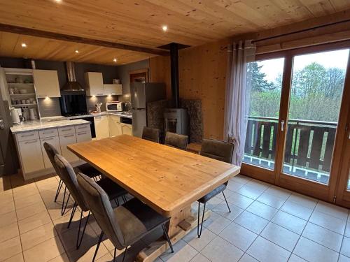 une cuisine avec une table en bois et quelques chaises dans l'établissement Chalet Les Bouleaux, la montagne des lamas, à La Bresse