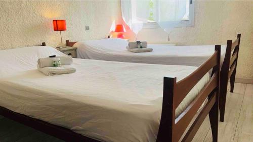 - une chambre avec 2 lits, des serviettes et une fenêtre dans l'établissement La Coccinelle, à Gujan-Mestras