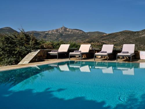 a swimming pool with chairs and a table and mountains at Villa Joy with private pool, close to Naoussa in Kóstos