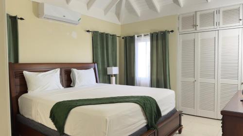a bedroom with a large bed with green curtains at Jamnick Vacation Rentals - Fern Court, Richmond Estate, St Ann, Jamaica in Ocho Rios