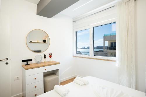 a white bedroom with a window and a mirror at The blue pearl apartment 2 in Durrës
