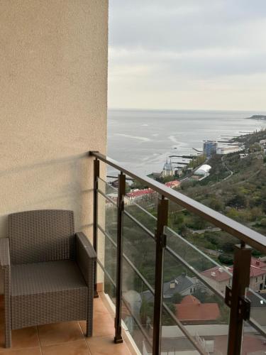 a balcony with a chair looking out at the ocean at Arcadia apartment & sea terrace in Odesa