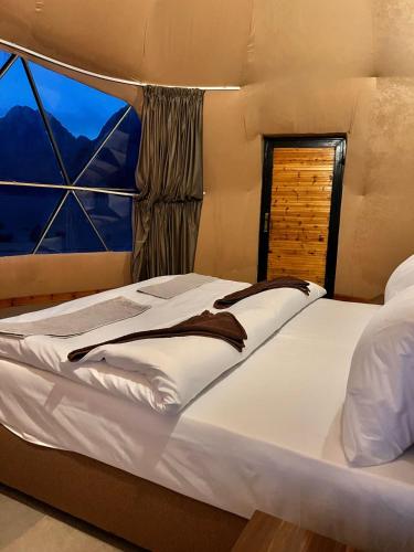 a bed in a room with a large window at Scarlet Luxury Camp Wadi Rum in Wadi Rum