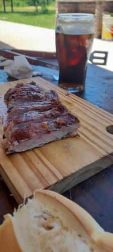 a piece of meat on a wooden cutting board with a drink at El Tropezón in Resistencia