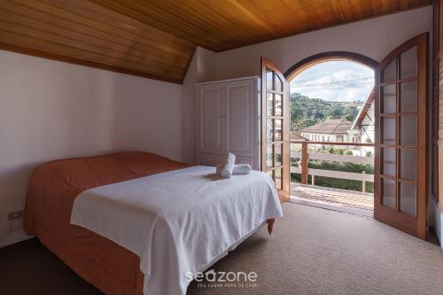 a bedroom with a bed and a large window at Casa espaçosa c/lareira em Campos do Jordão RAS175 in Campos do Jordão