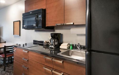 a kitchen with a sink and a black refrigerator at My Place Hotel-Bozeman, MT in Bozeman