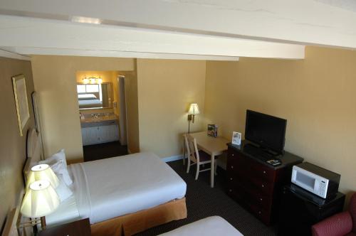 a hotel room with a bed and a desk with a television at Ambassadors Inn & Suites in Virginia Beach