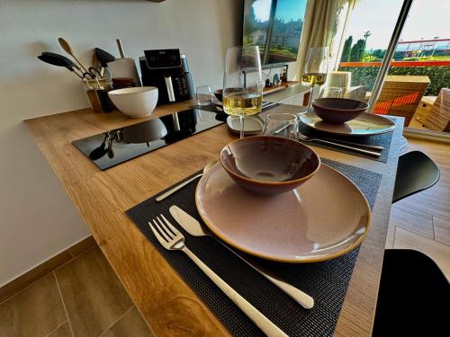 a table with a plate and wine glasses on it at Studio élégant et vue mer au Boucanet in Le Grau-du-Roi