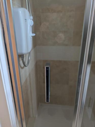 a shower with a glass door with a sink at The Crow's Nest in Mundesley