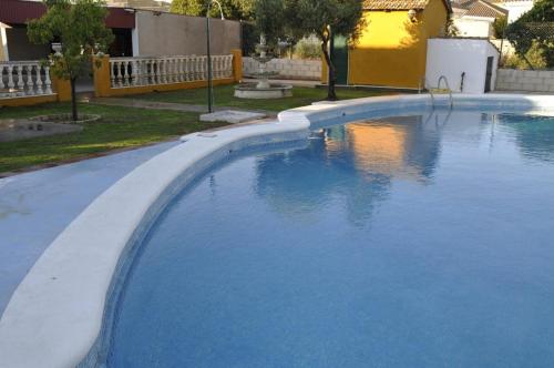 a large swimming pool with blue water in a yard at Casa Rural MATEOS in El Puerto de Santa María