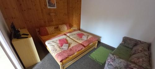 a small bedroom with a bed and a couch at Penzion U Dvou pánů in Pernink