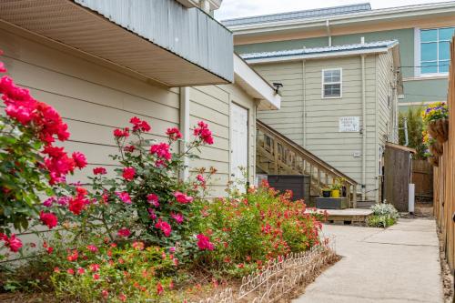 a garden with pink flowers next to a house at 23 Center St - Sunny Side Down - Downstairs Apartment in Folly Beach