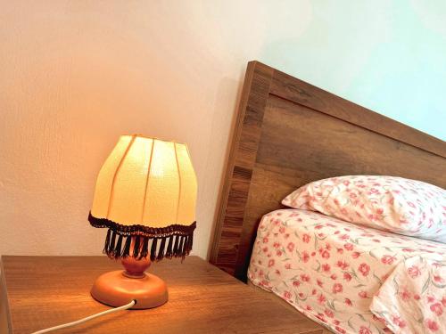 a lamp sitting on a table next to a bed at OLIVE Home in Durrës