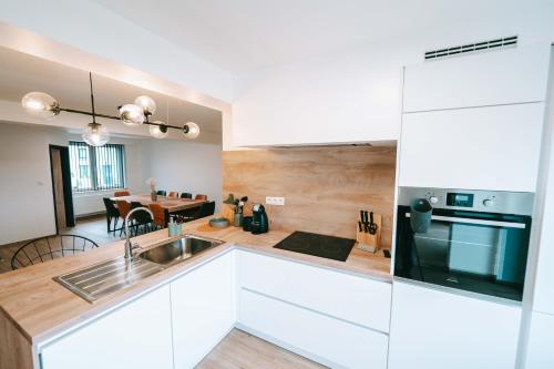 a kitchen with white cabinets and a dining room at L'Escapade des Lacs - Gite aux Lacs de l'Eau d'Heure in Cerfontaine