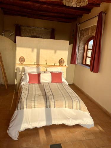 a bedroom with a large bed with two red pillows at Villa'S in Zaouiet Bouzarktoune