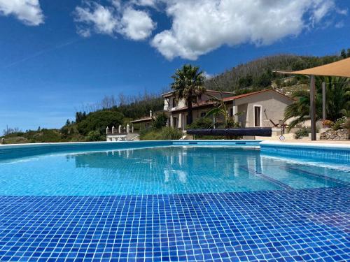 a large blue swimming pool with a house in the background at Quinta O Ninho Bed & Breakfast in Monchique