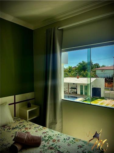 a bedroom with a bed and a large window at Apt Completo e Confortável 300mt Praia de Croa Vermelha in Coroa Vermelha
