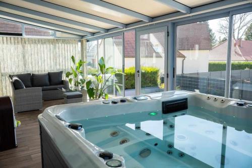 un jacuzzi dans un salon avec une grande fenêtre dans l'établissement Le Cocon de l'Île, à Dalhunden