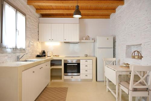 a kitchen with white appliances and a table and chairs at Cycladic Cottage II in Kanala