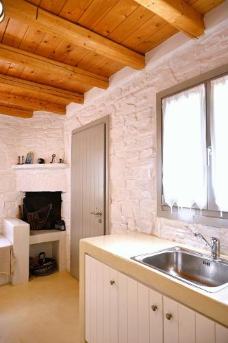 a kitchen with a sink and a fireplace at Kanala Sea-Side Cycladic Cottage II in Kanala