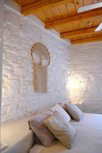 a bedroom with a stone wall and a bed with pillows at Kanala Sea-Side Cycladic Cottage II in Kanala