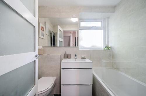 a white bathroom with a toilet and a sink at The Den in Croydon