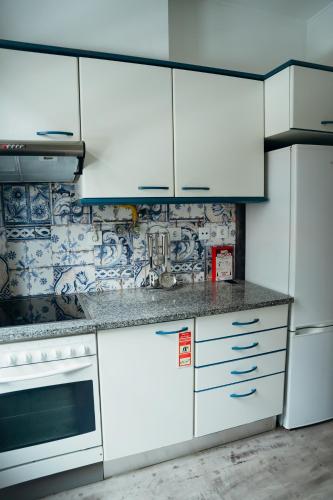 a kitchen with white cabinets and white appliances at Casa do Papel - Charm in Matosinhos in Matosinhos