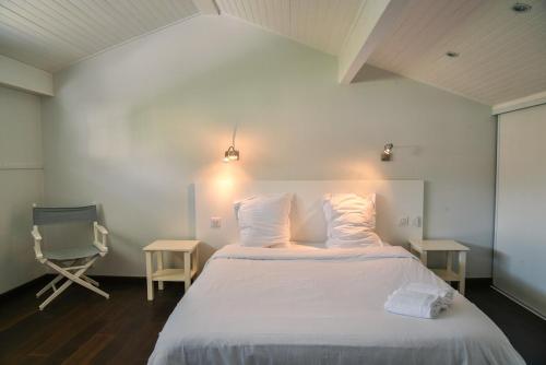 - une chambre avec un lit doté de draps blancs et d'une chaise dans l'établissement Villa contemporaine proximité plage et centre, à Capbreton