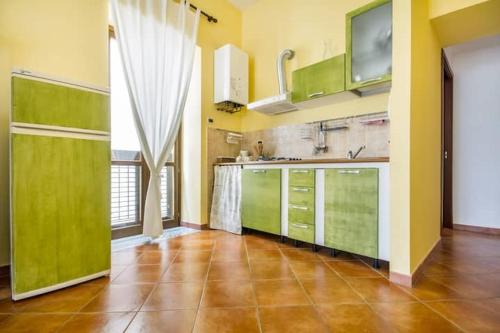 une cuisine avec des placards verts et une grande fenêtre dans l'établissement La Casetta del Vicolo, à Palerme