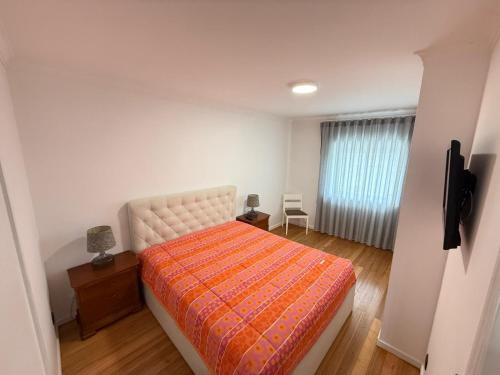 a bedroom with a bed with an orange blanket at By The Ocean in Póvoa de Varzim