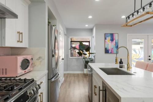 a kitchen with white cabinets and a pink microwave at Chic pool home 6 mi to beach sleeps 8 in Long Beach