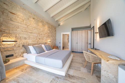 a bedroom with a white bed and a brick wall at Irena Stone Villas Kefalonia in Lourdhata