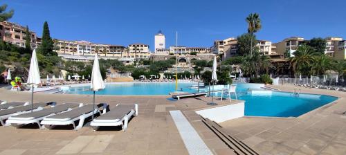 une piscine avec des chaises longues et un complexe hôtelier dans l'établissement T2 Vue mer, Jardin clos, Village vacances Cap Esterel St Raphaël, à Saint-Raphaël