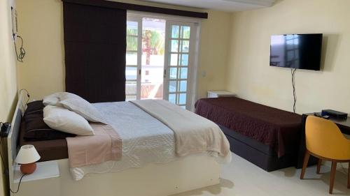 a bedroom with a bed and a desk and a television at GH Casa da Montanha RJ - Jacarepaguá in Rio de Janeiro
