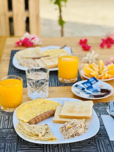 a table topped with plates of food and orange juice at Aquatic Mathiveri in Mathiveri