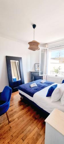 une chambre avec un grand lit et une chaise bleue dans l'établissement Appartement 42m2 - Calme & confort - Paris & aéroport d'Orly à 15 min, à Antony