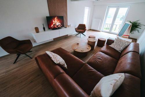 a living room with a brown couch and a fireplace at L'Escapade des Lacs - Gite aux Lacs de l'Eau d'Heure in Cerfontaine