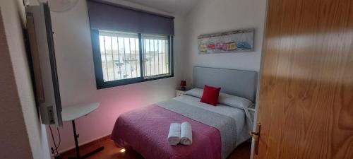 ein kleines Schlafzimmer mit einem Bett und einem Fenster in der Unterkunft Preciosa casa con piscina y golf in El Portil