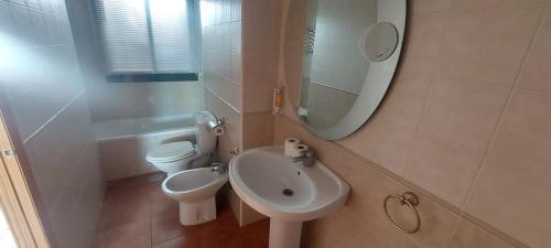ein Badezimmer mit Waschbecken, Toilette und Spiegel in der Unterkunft Preciosa casa con piscina y golf in El Portil