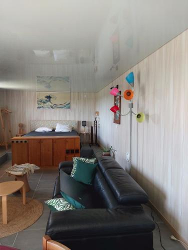 - un salon avec un canapé en cuir noir et un lit dans l'établissement appartement de plain-pied tout confort, à Carla-Bayle