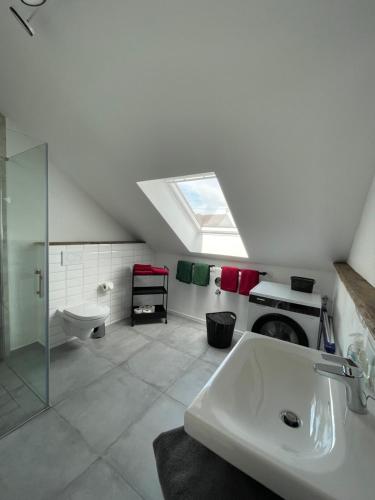 a bathroom with a sink and a toilet and a skylight at Eifel-Ferienhaus, Haus Achtzehn77 in Bitburg